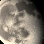 A Hold árnyékos oldala, éjszakai fényekkel és kráterekkel.