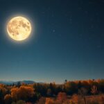 Betakarítási Hold szeptemberi éjszakai látképe hegyekkel és fák mögött.