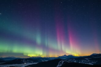 Éjszakai égbolt színes aurorával és csillagokkal.