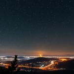 Éjszakai csillagos égbolt és városi fényszennyezés