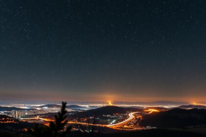 Éjszakai csillagos égbolt és városi fényszennyezés
