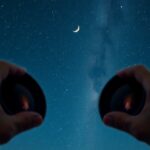 Két kézben tartott binokulár a csillagos ég alatt