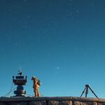 Csillagász a távcsövnél, csillagos égbolt alatt.