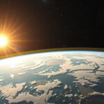 A Nap látható az űrből, a Föld felszíne és felhői mögött.